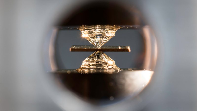 A diamond anvil crunches a material viewed through a microscope.