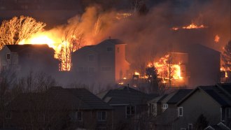A photo showing the flames of the Marshall Fire burning homes in a neighborhood at night.