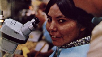 A Navajo woman sitting at a microscope
